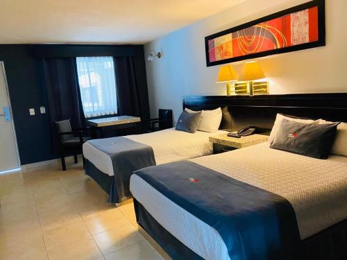 ein Hotelzimmer mit 2 Betten und einem Schreibtisch in der Unterkunft Hotel La Finca in Hermosillo