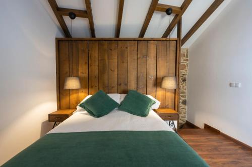 een slaapkamer met een groen en wit bed met 2 groene kussens bij Casa Xiana in Corcubión