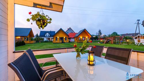 a table and chairs on a balcony with a view of a house at Łebskie Chatki in Łeba