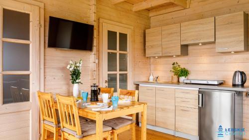 a kitchen with a wooden table with chairs and a television at Łebskie Chatki in Łeba