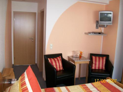 um quarto com duas cadeiras e uma cama e uma televisão em Haus-Anka em Cochem