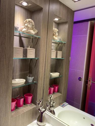 La salle de bains est pourvue d'un lavabo et d'un miroir avec des tasses roses. dans l'établissement Le Boudha Love, au Cap d'Agde