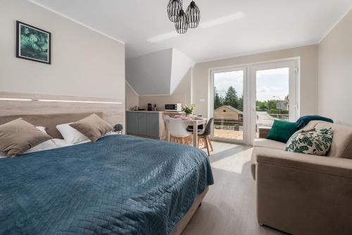 a bedroom with a bed and a couch and a table at Róża Bałtyku - Apartamenty i Pokoje A in Dębki