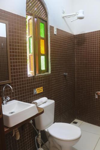 a bathroom with a toilet and a sink and a window at Hospedaria Flor de Caju in Pipa