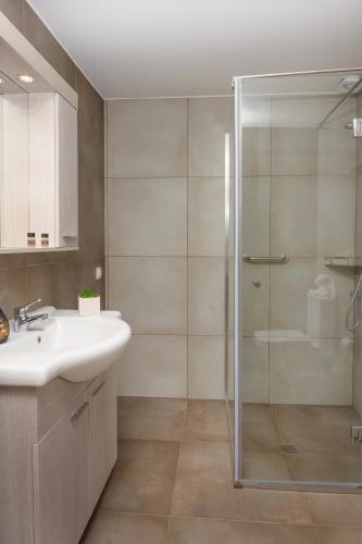 a bathroom with a glass shower and a sink at M&B boutique apartments in Nea Roda