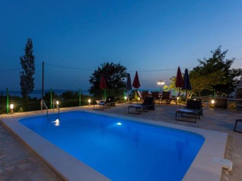 a swimming pool at night with chairs and umbrellas at Villa in Tu epi with Private Swimming Pool in Tučepi