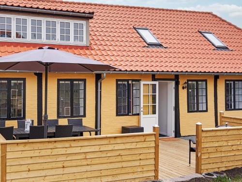a house with an orange roof and a wooden deck at 8 person holiday home in Allinge in Allinge