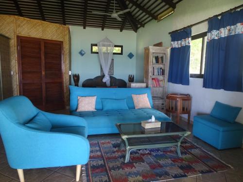 a blue couch and two chairs in a living room at Hôtel Atiapiti in Opoa