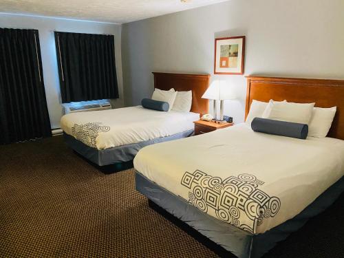 a hotel room with two beds with white sheets at Fleetwood Inn Suites in Cheboygan