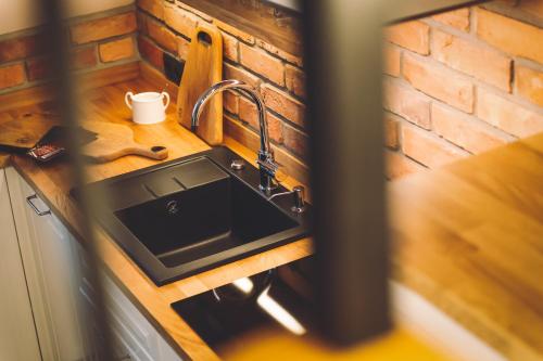 a kitchen counter with a sink and a brick wall at LEŚNA STRZECHA APARTAMENTY in Rotembark