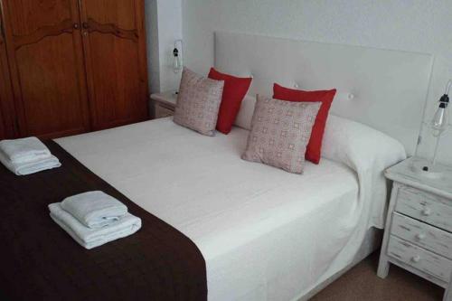 a bedroom with a large white bed with red pillows at El Pisuco in Dolores