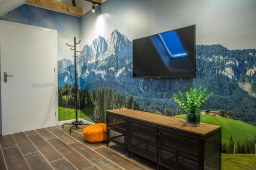 a room with a tv on a wall with a mountain mural at Willa Fen in Karpacz