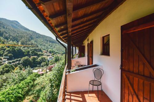 a balcony of a house with a chair and a door at Nations Gerês - Bed & Breakfast in Geres
