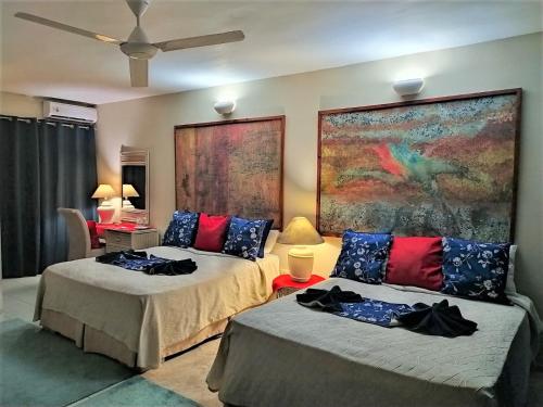 Hotel Coco Plaza في لاس تاريناس: غرفة نوم بسريرين ولوحة على الحائط