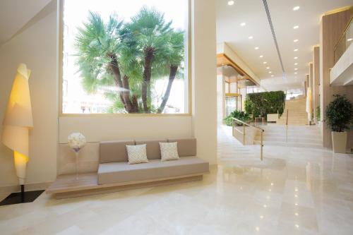 a lobby with a couch and a palm tree at Hotel Sabina in Cala Millor