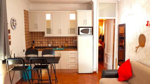 コスタ・デル・シレンチオにあるLoft Marfilの白いキャビネット、テーブルと椅子付きのキッチンが備わります。