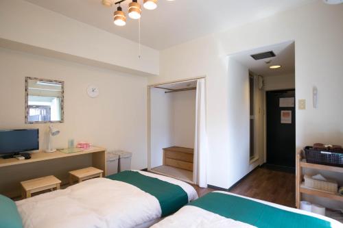 a bedroom with two beds and a desk and a television at Wings Hakata in Fukuoka
