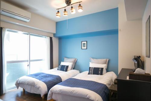 two beds in a room with a blue wall at Wings Hakata in Fukuoka