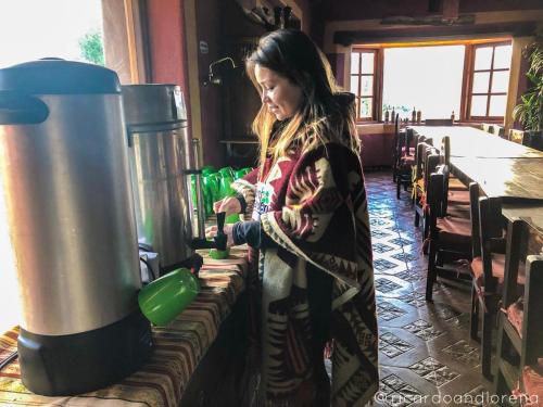 a woman standing in front of a stove in a kitchen at The Secret Garden Cotopaxi in Hacienda Porvenir
