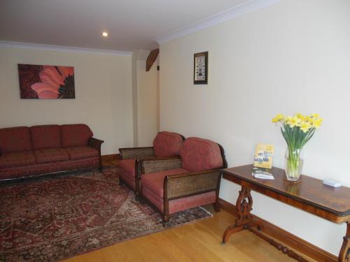 a living room with two couches and a table with flowers at Highfield Farm in Sandy