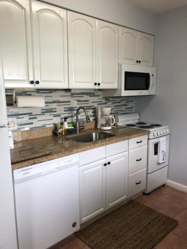 a kitchen with white cabinets and a sink and a microwave at Hollywood Beach and Boardwalk in Hollywood