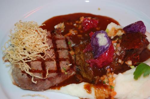 a plate of food with meat and strawberries and sauce at Parkhotel Krone in Emmendingen