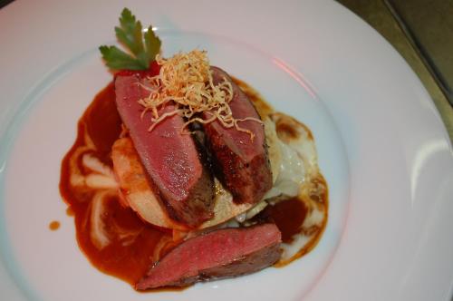 a white plate with a sandwich with meat and sauce at Parkhotel Krone in Emmendingen