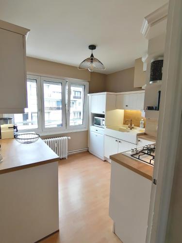 une cuisine avec des placards blancs et des comptoirs blancs dans l'établissement Face port proche nausicaa avec parking privé gratuit, à Boulogne-sur-Mer