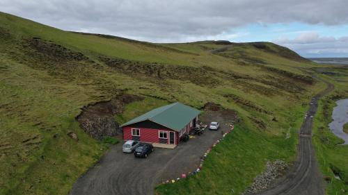 a red house on a hill with cars parked next to it at Valkyrie Guesthouse - 1km from SELJALANDSFOSS in Hvolsvöllur