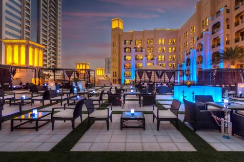 a patio with tables and chairs and buildings at night at Bahi Ajman Palace Hotel in Ajman 
