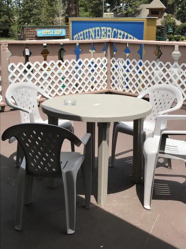 une table blanche et des chaises assises sur une terrasse dans l'établissement Thunderchief Inn, à South Lake Tahoe