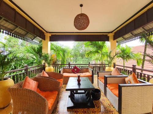 eine Veranda mit Korbstühlen und einem Couchtisch in der Unterkunft Residence Indochine Suite in Siem Reap