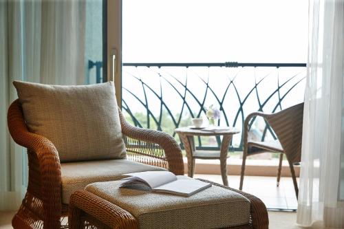 a room with a chair with a book on a ottoman at Lotte Hotel Jeju in Seogwipo