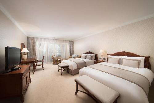 a hotel room with two beds and a television at Lotte Hotel Jeju in Seogwipo