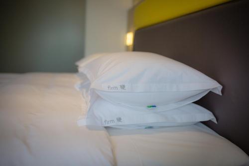a stack of white pillows sitting on a bed at Holiday Inn Express Emei Mountain by IHG in Emeishan