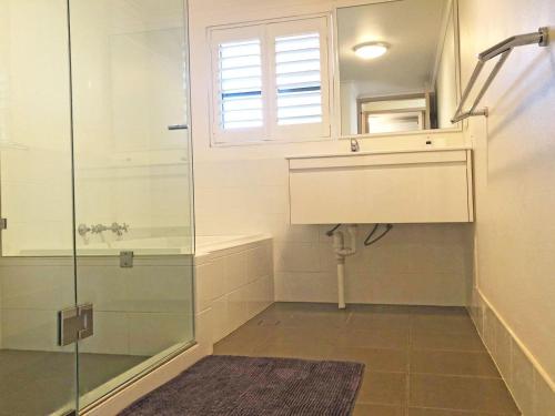 a bathroom with a shower and a sink and a window at The Poplars, 15,36 Magnus Street - Unit in a great complex with a pool and close to town in Nelson Bay