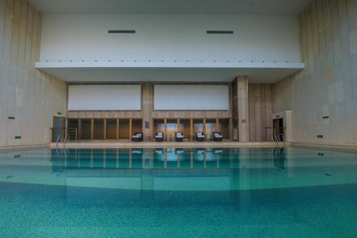 an empty swimming pool with chairs in a building at Gloria Resorts Jingdezhen Xishan Lake in Jingdezhen
