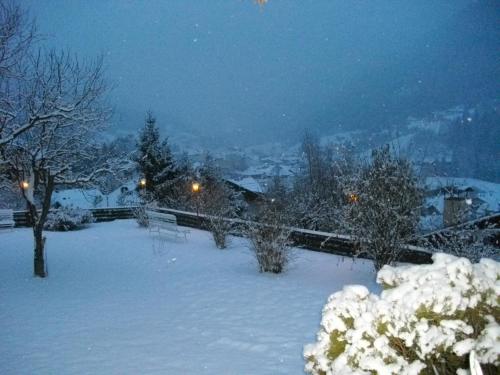 a snow covered yard at night with a city at Hotel Villa Emilia in Ortisei