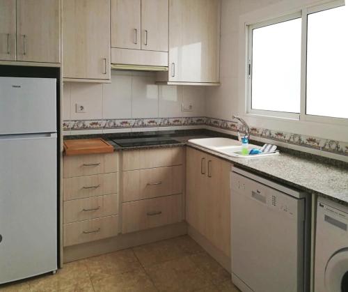eine Küche mit weißen Schränken, einem Waschbecken und einem Fenster in der Unterkunft A3A Marina View in Torredembarra