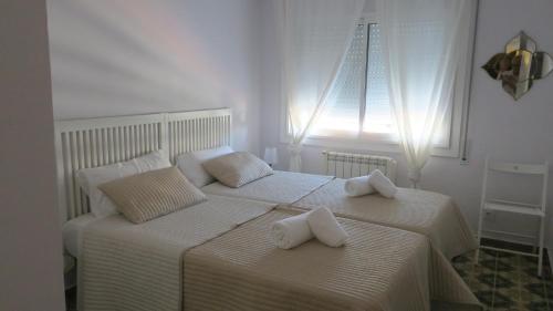 two beds in a bedroom with white sheets and pillows at A3A Marina View in Torredembarra