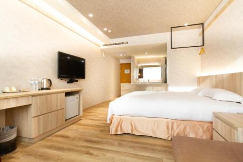 a hotel room with a bed and a flat screen tv at Daniel Motel in Xinying