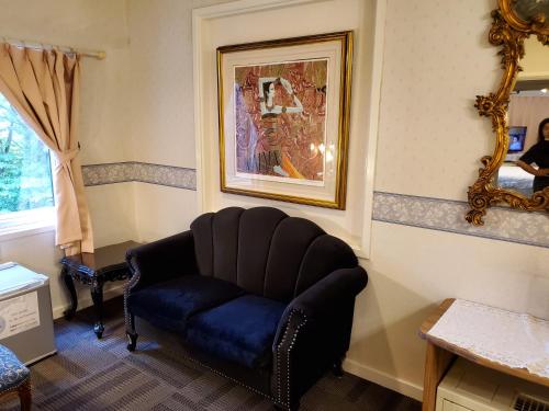 a living room with a blue chair and a mirror at プチホテル葡萄屋 in Hakuba