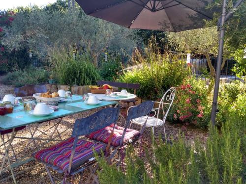 a table and chairs under an umbrella in a garden at Mas de Camejean in Lambesc