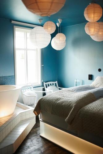 a bedroom with a bed with blue walls and lights at Huskvarna Stadshotell in Huskvarna