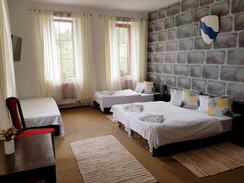 Hotel Camelot في تيسا: غرفة نوم بسريرين وغرفة بها كرسيين