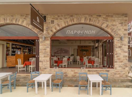 a restaurant with tables and chairs in front of a store at Parthenon Rooms in Koroni