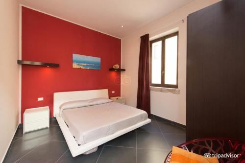トラーパニにあるパラッツォ デイ コルサリの赤い壁の白いベッドが備わるベッドルーム1室