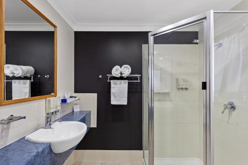 bagno con lavandino e doccia in vetro di Eastgate on the Range Motel a Toowoomba