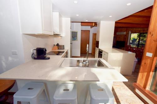 a kitchen with a sink and a counter with stools at Sublime Cedar Lodge Leura in Leura