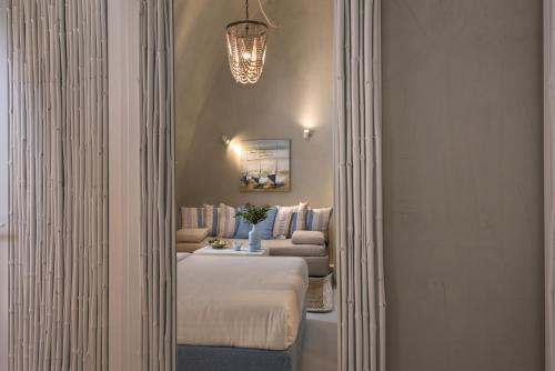 a hallway with a bed and a couch in a room at Mythical Blue Luxury Suites in Fira